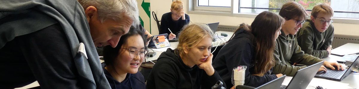 Schüler*innen arbeiten in Gruppen an Laptops