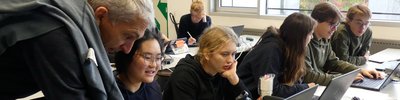 Schüler*innen arbeiten in Gruppen an Laptops