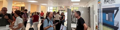 Teilnehmende im Gespräch am XLAB-Infostand